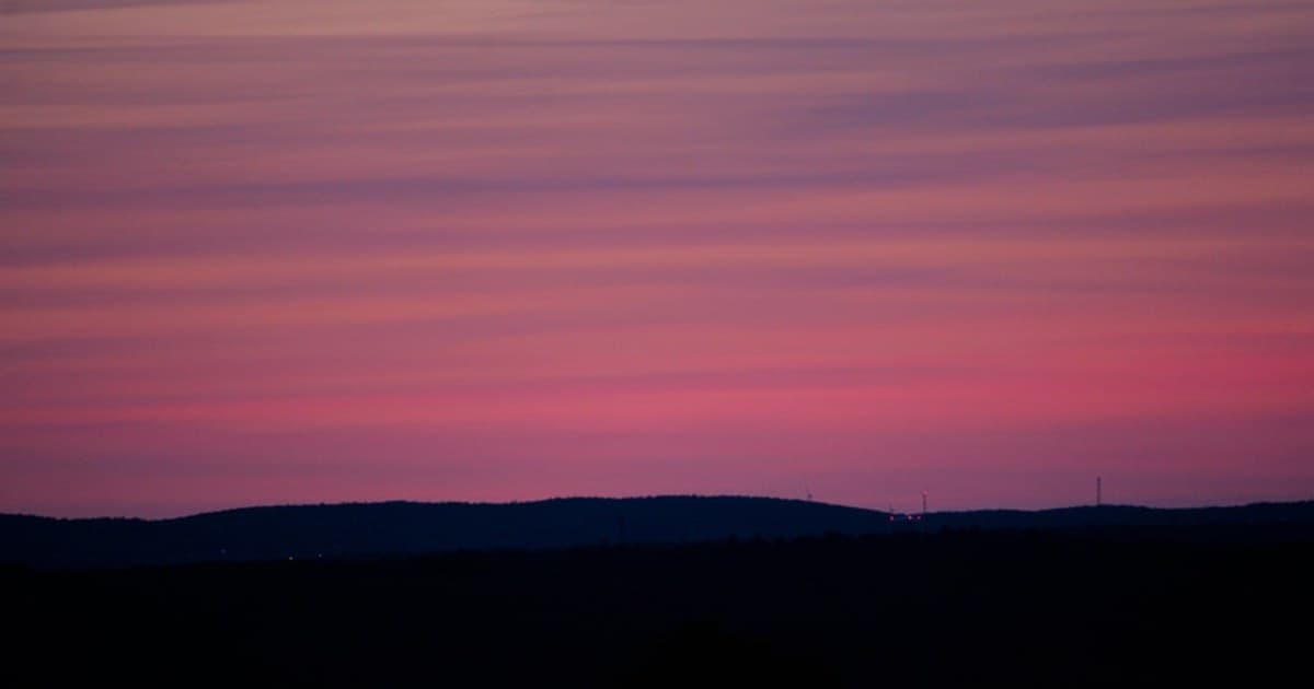 the sun is setting over a mountain range