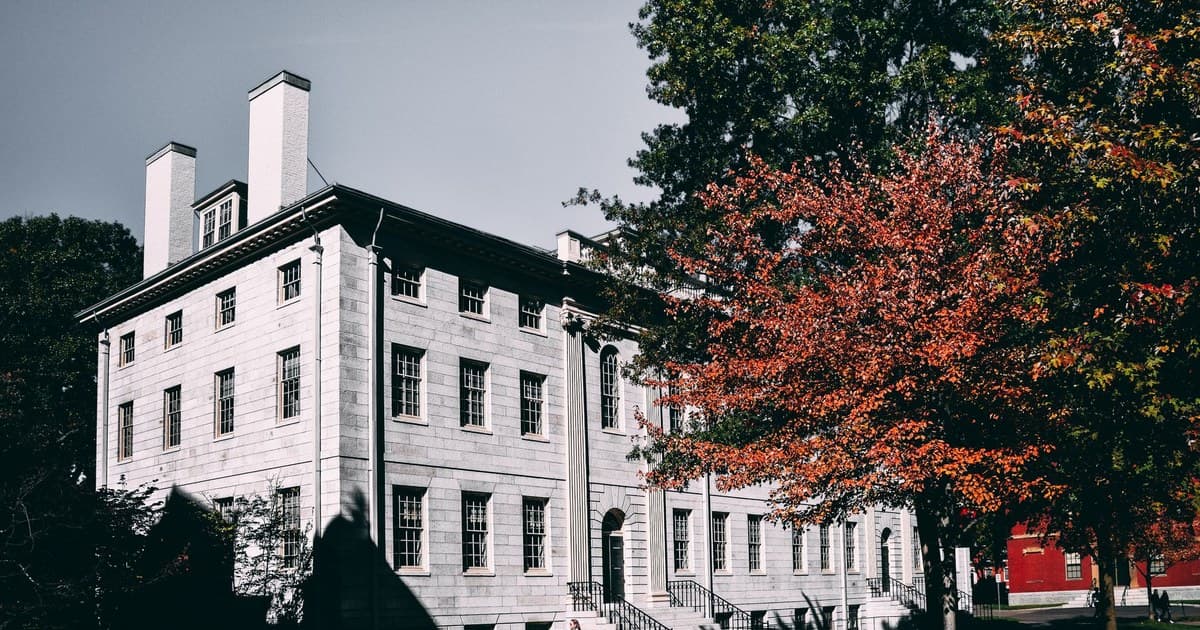 A classic stone mansion surrounded by vibrant fall trees, showcasing architectural elegance in a city park.